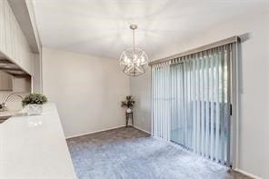 empty room featuring a chandelier and carpet