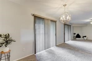 carpeted spare room with an inviting chandelier