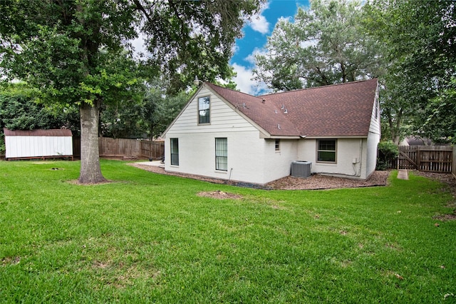 back of property with a shed, a yard, and central air condition unit