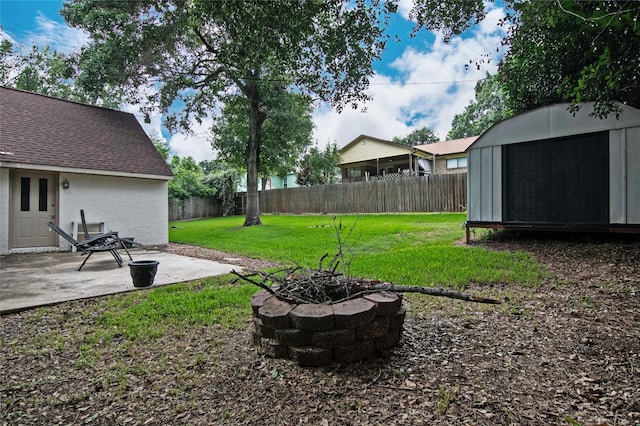 view of yard featuring a fire pit, a shed, and a patio