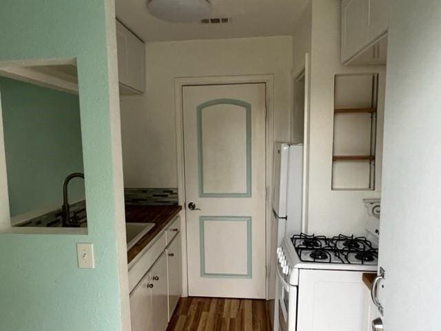 kitchen featuring white cabinetry, white range with gas stovetop, visible vents, and dark wood finished floors