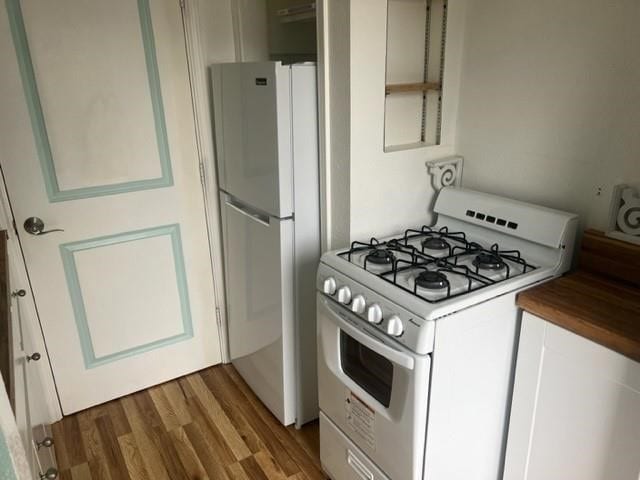 kitchen with white appliances, white cabinetry, and wood-type flooring