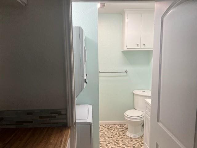 bathroom with washer / dryer, baseboards, and toilet