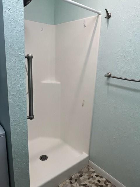 full bathroom with a stall shower and baseboards