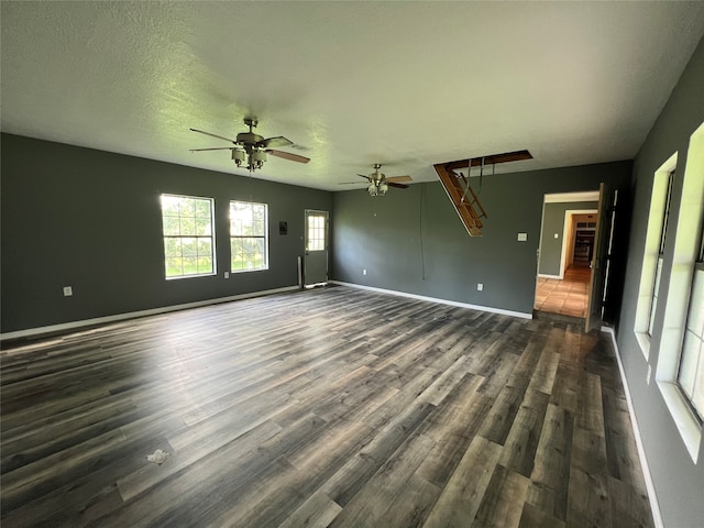 unfurnished living room featuring ceiling fan, a textured ceiling, and dark wood-type flooring