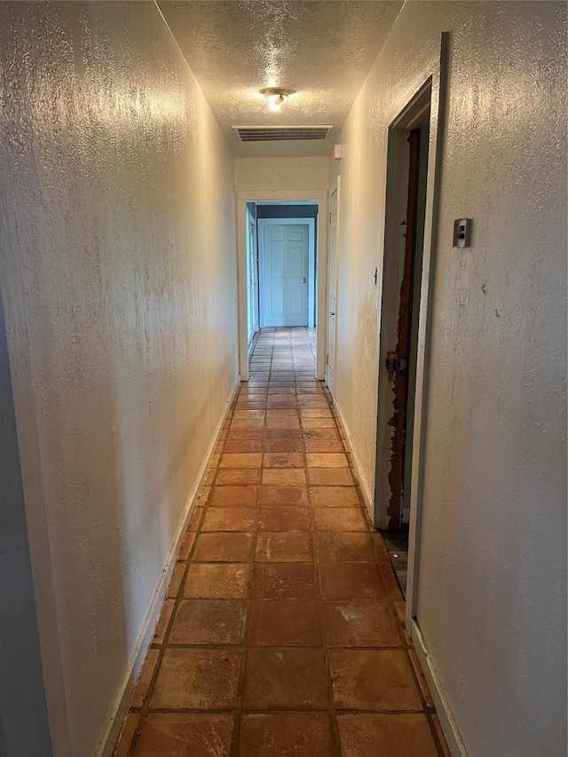 hall featuring tile flooring and a textured ceiling