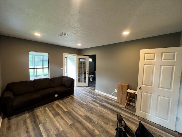 living room with a textured ceiling and dark wood-type flooring