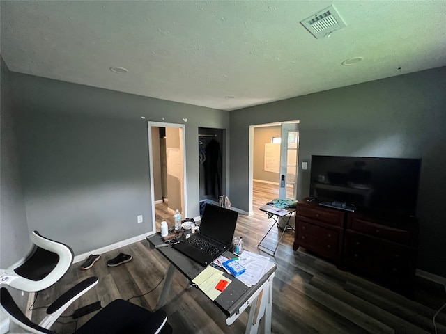 home office with a textured ceiling and dark wood-type flooring