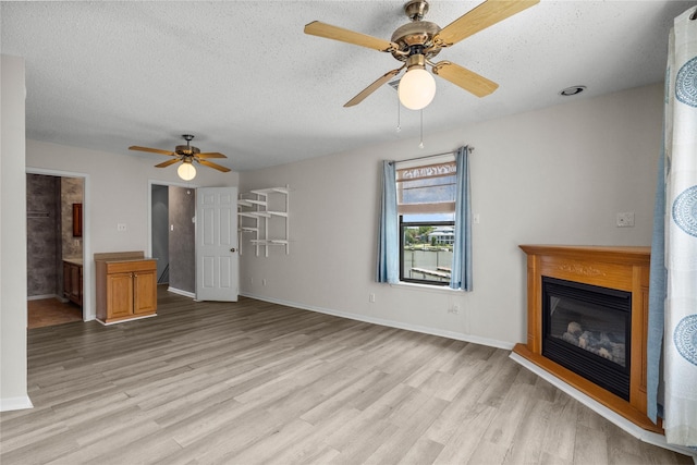 unfurnished living room with ceiling fan, light hardwood / wood-style flooring, and a textured ceiling