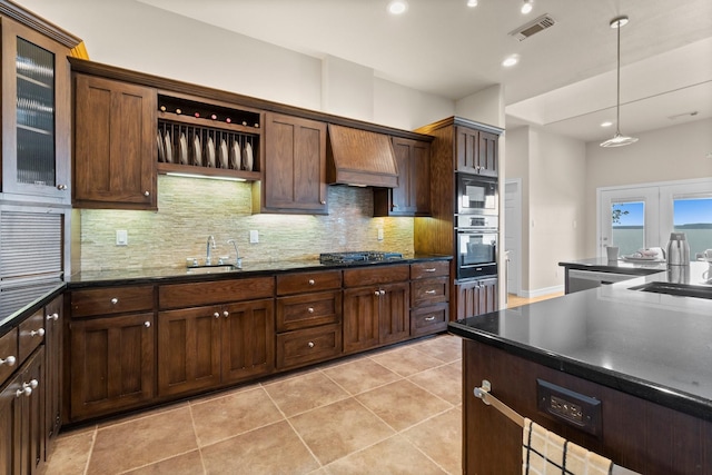 kitchen with wall chimney exhaust hood, decorative light fixtures, sink, oven, and built in microwave