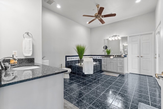 bathroom featuring ceiling fan, vanity, and a washtub