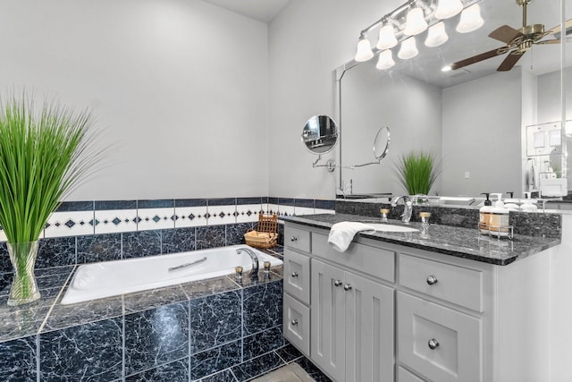 bathroom featuring ceiling fan, tiled tub, and vanity