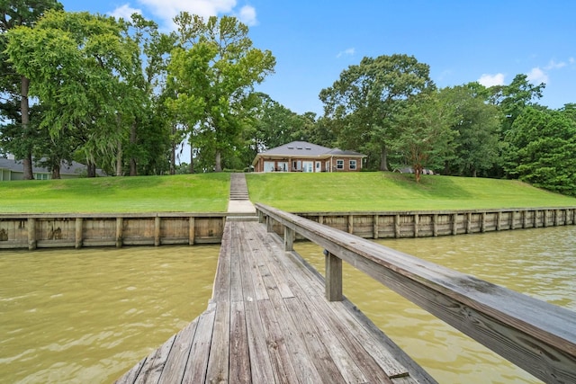 view of dock with a water view and a lawn