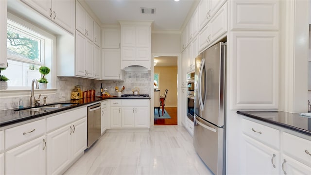 kitchen featuring tasteful backsplash, white cabinets, light hardwood / wood-style floors, appliances with stainless steel finishes, and sink