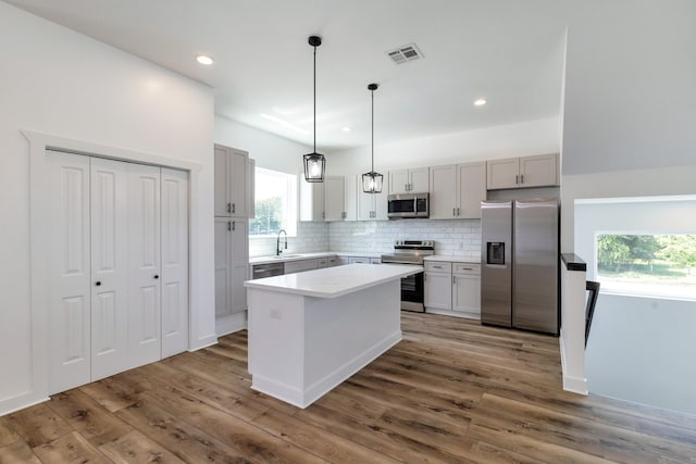 kitchen featuring appliances with stainless steel finishes, a center island, wood-type flooring, and a healthy amount of sunlight