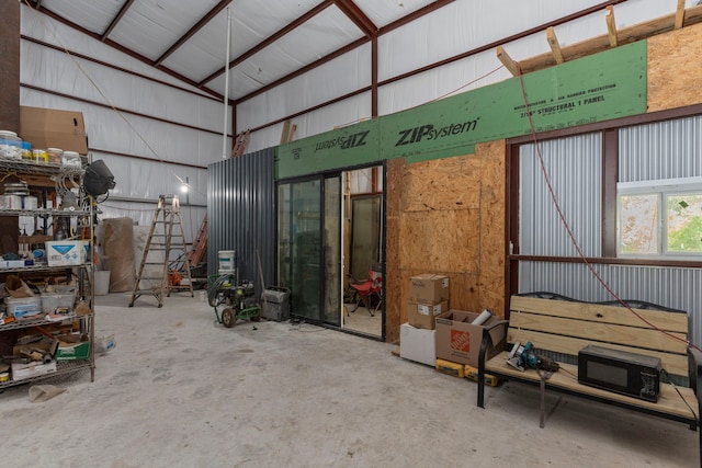 interior space featuring lofted ceiling, concrete floors, and metal wall