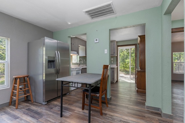 dining room featuring a textured wall, visible vents, and dark wood finished floors