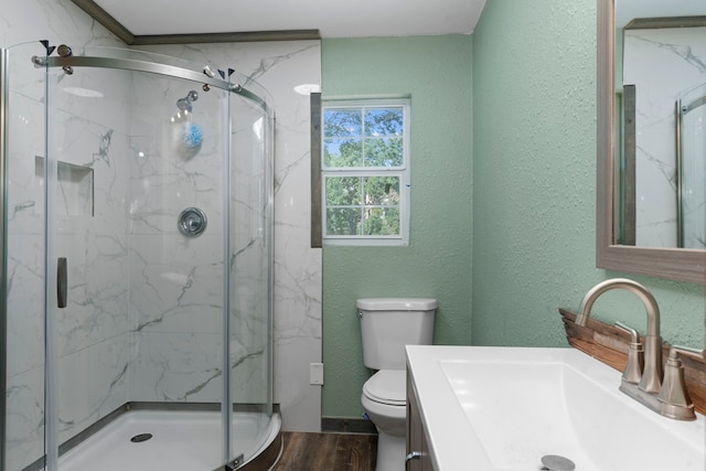 bathroom featuring a marble finish shower, wood finished floors, and a textured wall