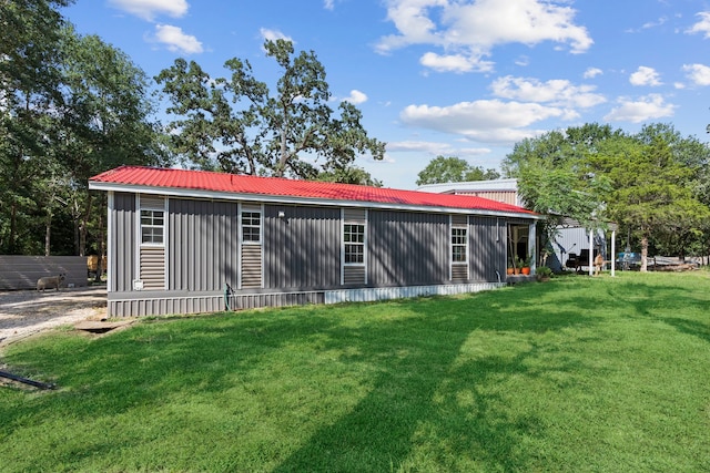 rear view of property featuring board and batten siding, metal roof, and a lawn