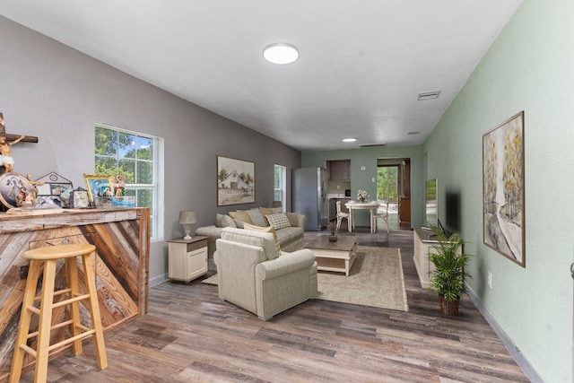 living room with a dry bar, dark wood-style flooring, visible vents, and baseboards