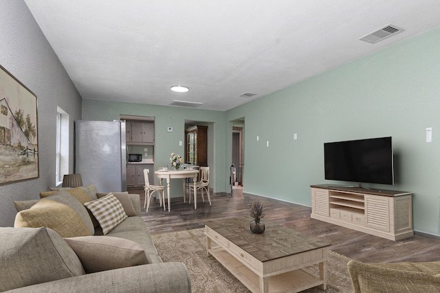 living area featuring baseboards, visible vents, and dark wood-style flooring