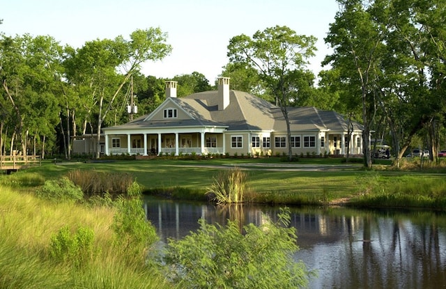 rear view of house featuring a yard and a water view