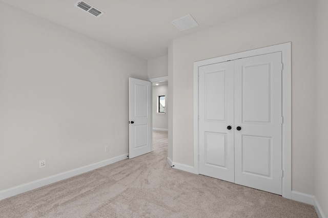 unfurnished bedroom featuring light colored carpet and a closet