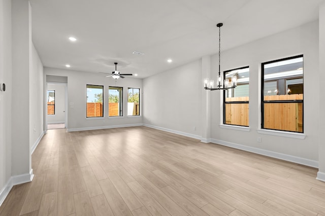 unfurnished living room featuring ceiling fan with notable chandelier and light hardwood / wood-style flooring