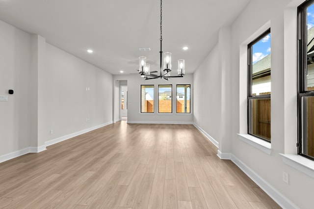 unfurnished dining area with a healthy amount of sunlight, light hardwood / wood-style floors, and an inviting chandelier