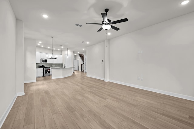 unfurnished living room featuring ceiling fan, sink, and light hardwood / wood-style flooring