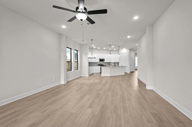 unfurnished living room featuring light wood-type flooring, ceiling fan, and sink