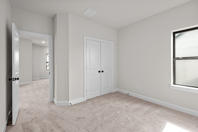 unfurnished bedroom with light carpet, a closet, and multiple windows