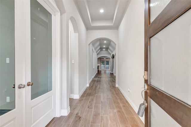 hallway featuring a raised ceiling and light hardwood / wood-style flooring