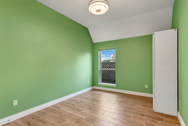 unfurnished room with light wood-type flooring and vaulted ceiling