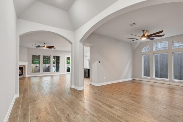 unfurnished living room with light hardwood / wood-style floors, ceiling fan, and lofted ceiling