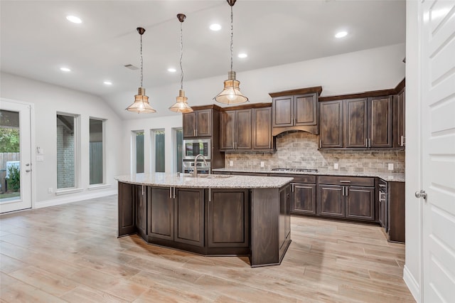 kitchen with appliances with stainless steel finishes, light wood-type flooring, dark brown cabinetry, sink, and decorative light fixtures