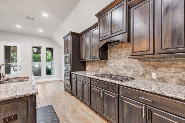 kitchen with decorative backsplash, stainless steel appliances, vaulted ceiling, sink, and light hardwood / wood-style flooring