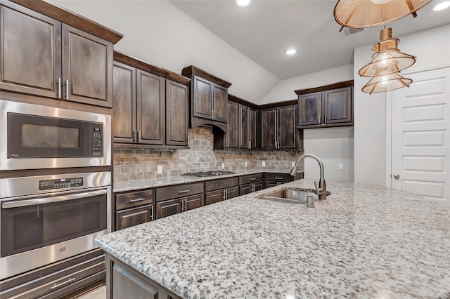 kitchen featuring light stone countertops, dark brown cabinetry, stainless steel appliances, sink, and decorative light fixtures