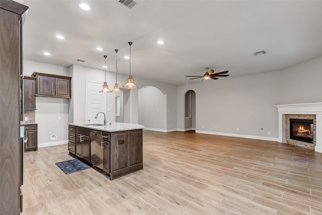 kitchen with pendant lighting, a center island with sink, light hardwood / wood-style flooring, stainless steel dishwasher, and ceiling fan