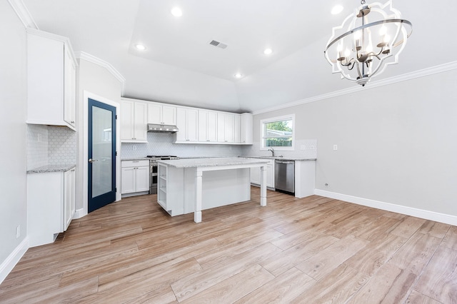 kitchen with appliances with stainless steel finishes, vaulted ceiling, light hardwood / wood-style floors, decorative light fixtures, and a kitchen island