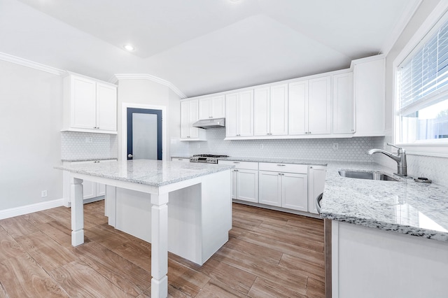 kitchen with tasteful backsplash, vaulted ceiling, a kitchen island, crown molding, and a kitchen breakfast bar