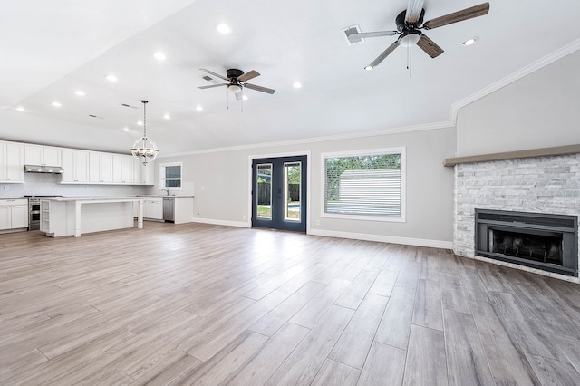 unfurnished living room with a fireplace, ceiling fan with notable chandelier, crown molding, french doors, and light hardwood / wood-style flooring