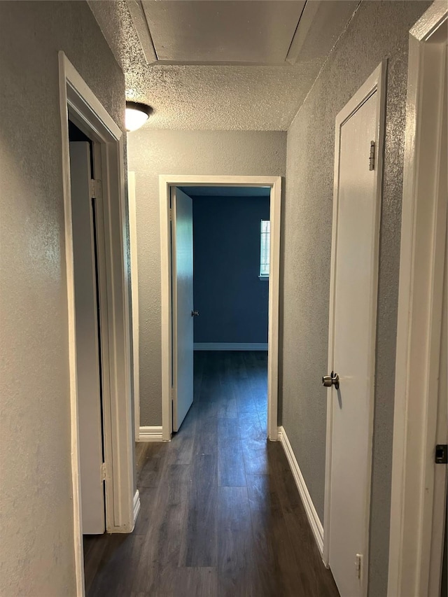 hallway with dark hardwood / wood-style floors and a textured ceiling