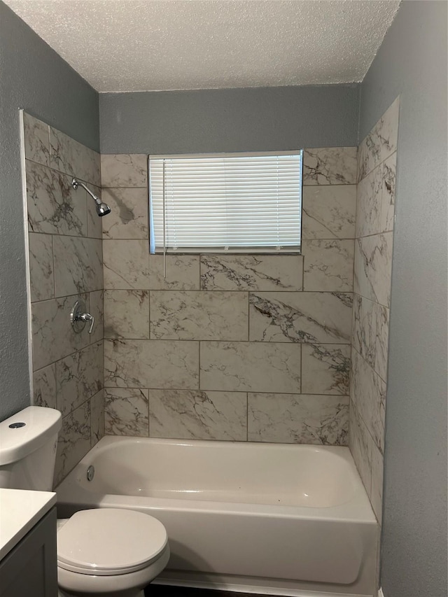 full bathroom with a textured ceiling, toilet, tiled shower / bath combo, and vanity