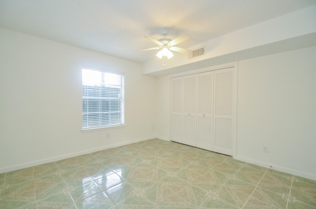 unfurnished bedroom featuring ceiling fan and a closet