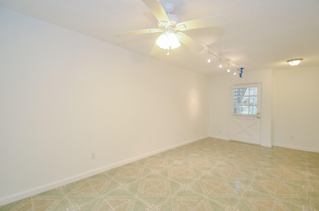 empty room with ceiling fan and track lighting