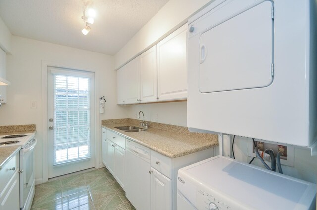 clothes washing area with a textured ceiling, sink, and stacked washer and clothes dryer