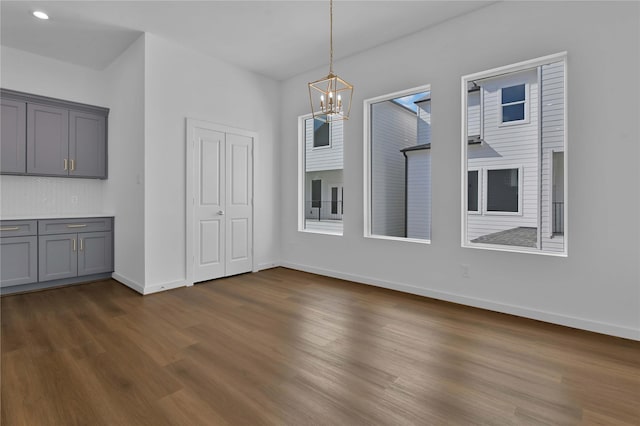 unfurnished dining area with dark wood-type flooring and a chandelier