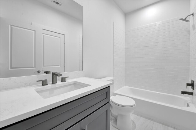 full bathroom with tiled shower / bath combo, vanity, and toilet