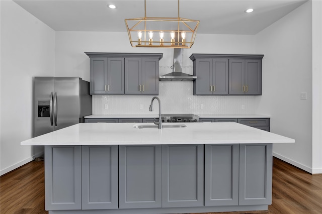 kitchen with dark wood-type flooring, wall chimney range hood, gray cabinetry, and tasteful backsplash